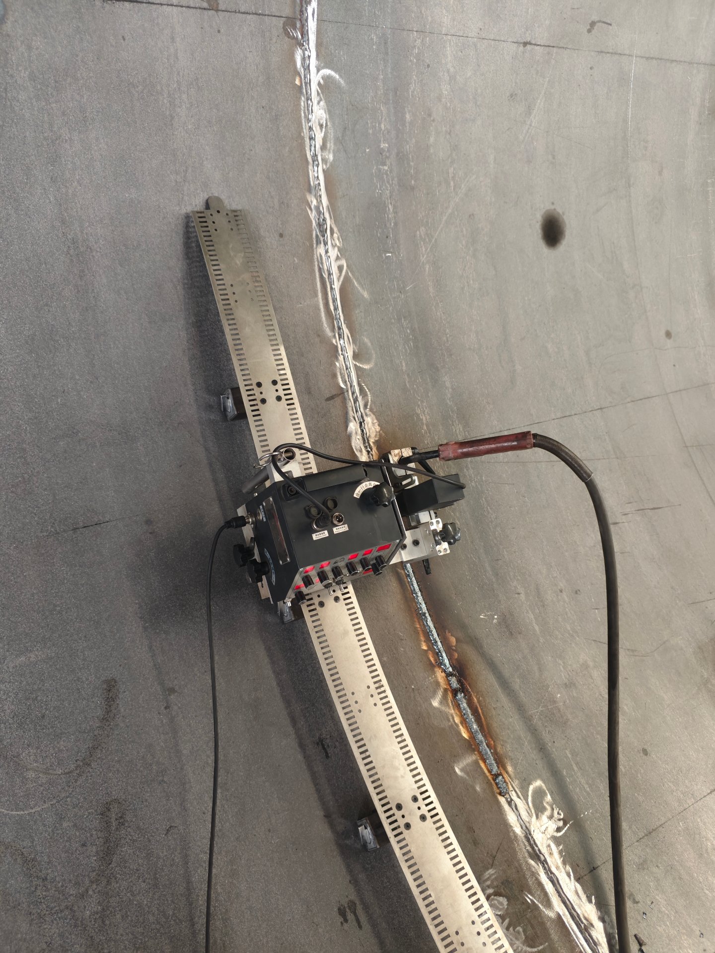 Flexible-track welding carriage working a vertical seam on a tank shell